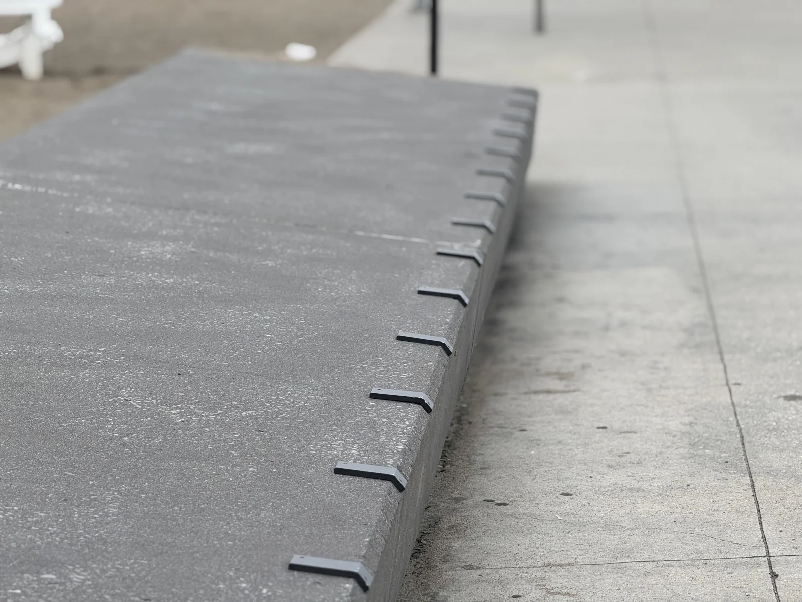 Dissuasifs skateboard installés le long d'un rebord en béton peint avec profil anti-glisse dentelé dans une place commerciale canadienne